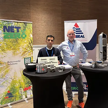 Two employees stand in front of AESSEAL banners and present mechanical seals.